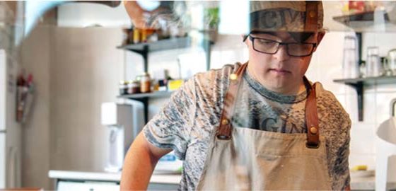 A young man with Down syndrome works in a cafe
