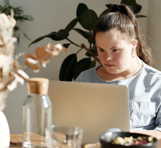 a woman with down syndrome works on a laptop